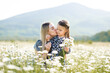 © morrowlight - Cute mother kissing child girl daughter in meadow with blooming flowers outdoor together. Family lifestyle. Motherhood. Summer season.