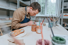 Young Man Working With Clay Making A Decorative Plate