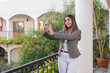 © Hugo - Young business girl taking a selfie on a hotel balcony.