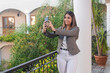 © Hugo - Young smiling business girl taking a selfie on a hotel balcony.