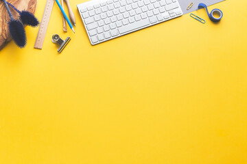 Wall Mural - Workspace yellow table with keyboard, wooden accessories and plant top view.	