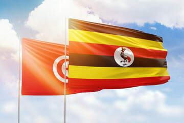 Sunny blue sky and flags of uganda and tunisia