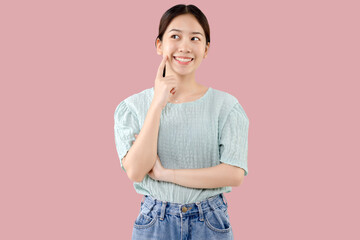 Beautiful young Asian girl thinking and looking upwards. The concept of content thinks about future isolated on pink background.