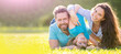 Banner of Happy family Lying on grass. Young mother and father with child son in the park resting together on the green grass. Family having fun outdoor in summer.