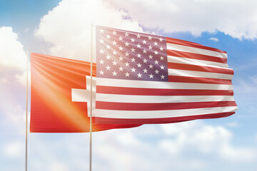 Sunny blue sky and flags of united states of america and switzerland