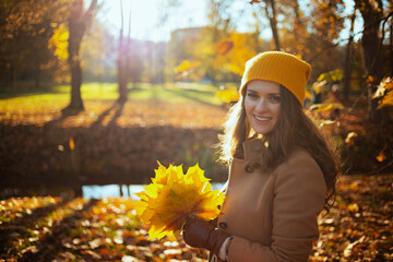 Wall Mural - happy modern 40 years old woman in brown coat and yellow hat