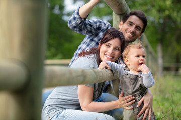 young couple with a baby feeding animals at the zoo