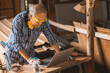 © Quality Stock Arts - Senior builder wood worker using laptop computer at aiding design at construction work.