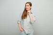 © Yuriy Shevtsov - Thinking serious woman touching her face and looking away, isolated female portrait, young lady dressed pants and gray shirt.