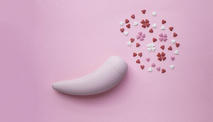 Wall Mural - Pink vacuum stimulator toy for adults lies on a pink background, next to the decorative hearts mimic an orgasm. Conceptual photo.