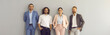 © Studio Romantic - Banner with group portrait of happy confident corporate employees looking at camera and smiling. Team of four positive young business people in smart office wear standing together against studio wall