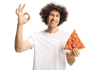 Cheerful young man holding a slice of pizza and gesturing sign for good, tasty,