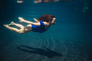 Wall Mural - Young woman swimming underwater in the swimming pool