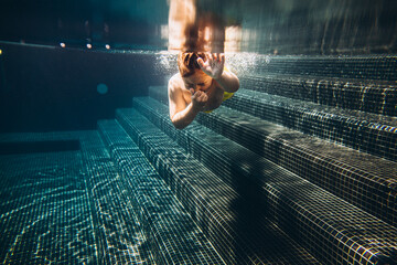 Wall Mural - the child swims and dives in the pool. Selective focus..