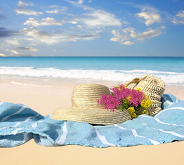  woman straw hat and bag  wild pink flowers on blue blanket at white sand in beach blue sky  and green sea water summer bakcground