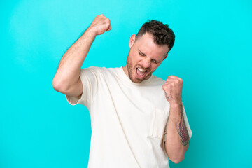 Canvas Print - Young Brazilian man isolated on blue background celebrating a victory