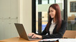 © Prathankarnpap - Smiling young woman in business suit using laptop computer at her workplace