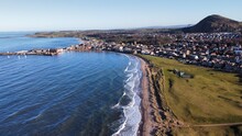 Aerial View Looking Out Over North Berwick Town And Golf Course With Waves Crashing Onto The Shore. North Berwick Scotland. 