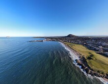 Aerial View Looking Out Over North Berwick Town And Golf Course With Waves Crashing Onto The Shore. North Berwick Scotland. 