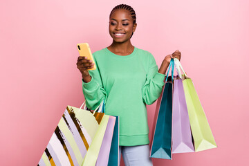 Sticker - Portrait of cheerful shopaholic girl use telephone hold packages isolated on pink color background