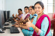 © WESTOCK - group of smiling women showing thumbs up by looking camera during computer training class - concept of women employment, learning and education