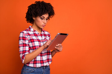 Poster - Photo of calm serious person use tablet typing email coworking empty space ad isolated on orange color background