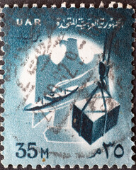 Wall Mural - EGYPT - CIRCA 1961 : a postage stamp from EGYPT , showing the loading of goods onto a ship and the state emblem. Circa 1961