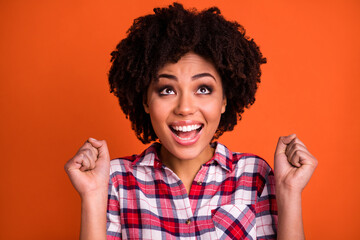 Sticker - Photo of funny adorable lady dressed checkered shirt rising fists looking up empty space isolated orange color background