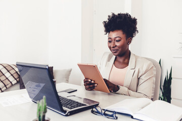 Cropped shot of an attractive young businesswoman sitting alone in her home office and using a tablet. Shot of a young woman working at home with a digital tablet.