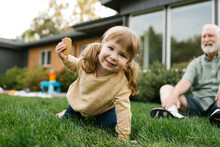 Smiling Girl (4-5) On Lawn, Grandfather In Background