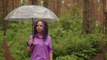 A Woman With An Umbrella In Her Hand In The Rain. A Girl In A Purple Shirt Under