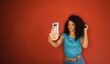 Afro hairstyle black woman taking selfie photo on red wall background.