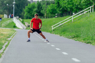 Wall Mural - Handsome young man stretching and warming up before for morning workout  in the park