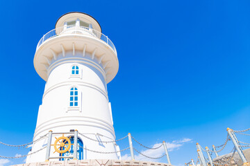 Low angle view of white lighthouse in Alanya, Turkey. Beautiful beacon under blue sky on sunny day. Selective focus.