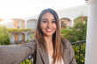 © Hugo - Selfie of a smiling business girl on a hotel balcony.