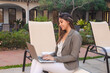 © Hugo - Young business girl working with her laptop in a hotel courtyard.