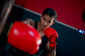 Close up Asian man point red mitt of punch and also look at camera in sport gym. Concept of boxing exercise for good health.