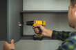 © alexanderon - Furniture maker uses a screwdriver to attach a door to a cabinet. New furniture assembling