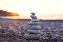 Pyramid Of Stones On The Beach. Perfect Balance Of Stack Of Pebbles At Seaside Towards Sunset. Concept Of Balance, Harmony And Meditation. Helping Or Supporting Someone For Growing Or Going Higher Up.