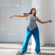 © Ulia Koltyrina - Modern dance, stylish young brunette in baggy blue pants dancing in jazz-funk style. Stylish and youthful. The dance hall is illuminated by sunlight, bright colors