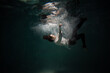 Sink. A young guy in a white shirt falls into the water, a photo from under the water. The concept of falling down, diving to the depth, contrasting dark photo