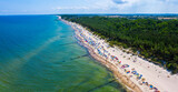 Wybrzeże morza bałtyckiego i piaszczysta plaża z opalającymi i kąpiącymi się plażowiczami w miejscowości Sarbinowo, widok z lotu ptaka