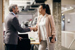 © Drazen - Asian businesswoman handshaking with mature businessman at corporate office.