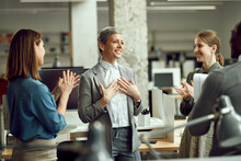 Happy Businesswoman Feels Grateful While Group Of Colleagues Are Applauding Her In Office.