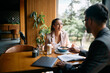 © Drazen - Happy businesswoman talks to colleague while eating breakfast in cafe.