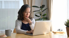 Concentrated Middle Aged Woman Watching Online Webinar, Working At Home With A Laptop Computer