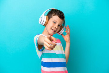 Wall Mural - Little boy isolated on blue background listening music and pointing to the front