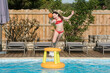 cute young girl playing with inflatable basketball hoop in swimming pool