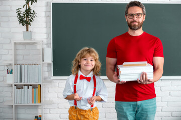 Fototapete - School education and children concept. Pupil of primary elementary school has lesson. Kid boy with teacher learn english language or mathematics. Happy kid student at school lesson.