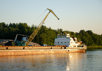 Floating crane in the river port on a summer day. The concept of export and import of goods